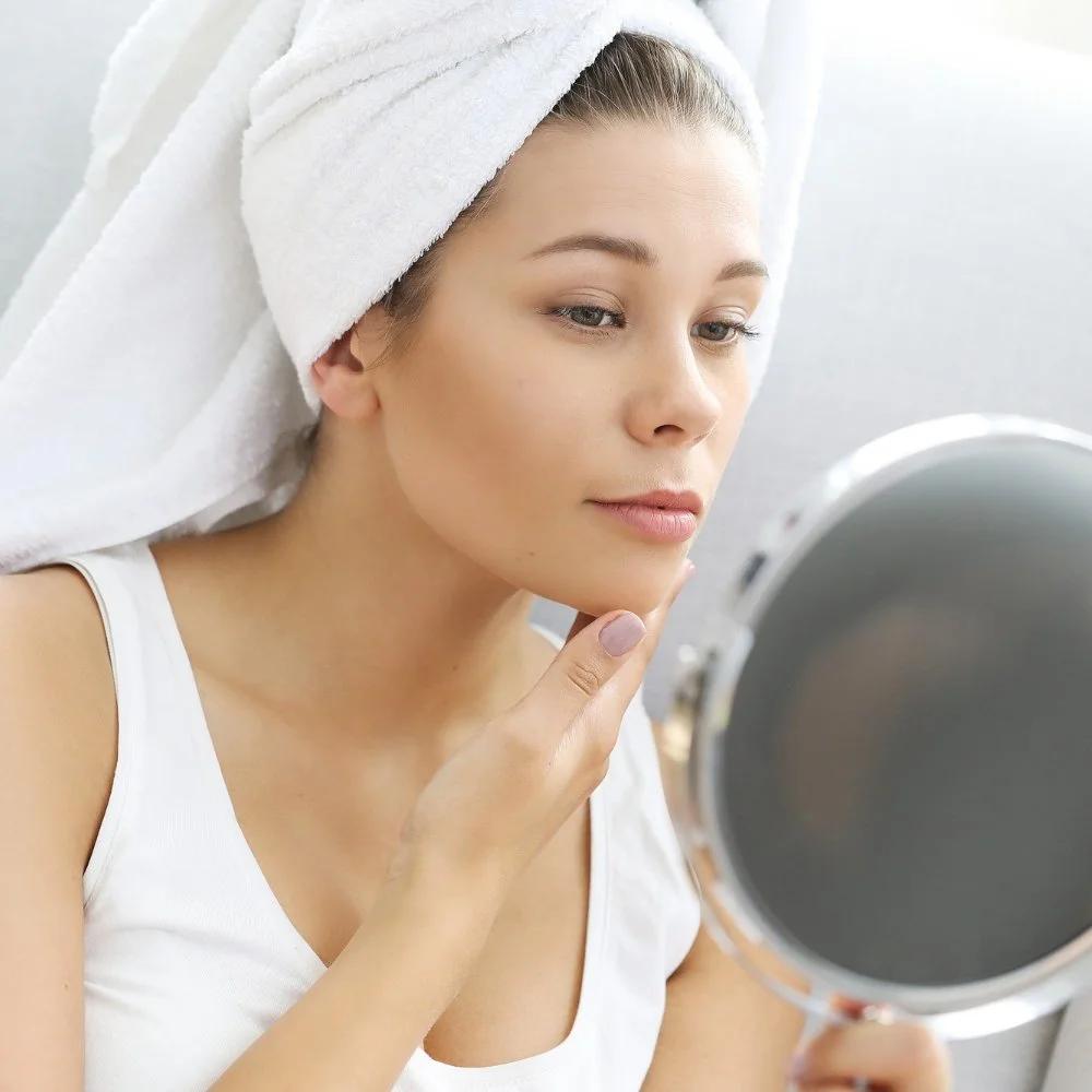 Moteris žiūri į savo veidą veidrodyje