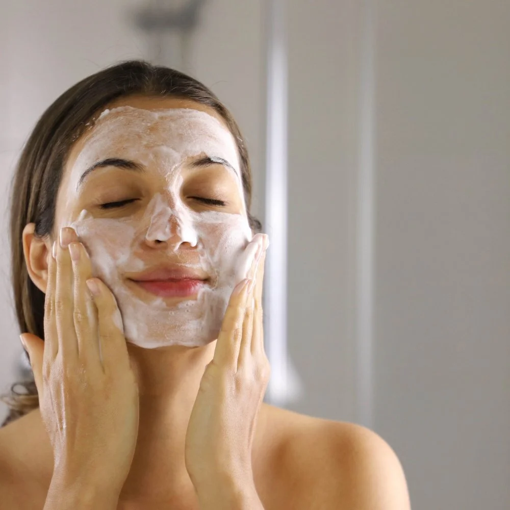 Moteris valo veidą rankomis su valomosiomis putomis